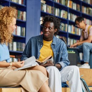 Stedents in the library having a disussion about words and what they mean.